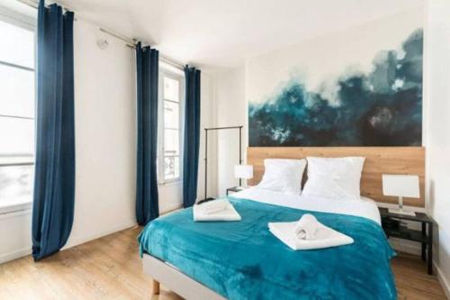 um quarto com uma cama grande e lençóis azuis em Nets Inn Apartments - La Villette em Paris