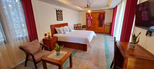 een slaapkamer met een bed, een stoel en een tafel bij Pink Tulip Hoi An in Hội An