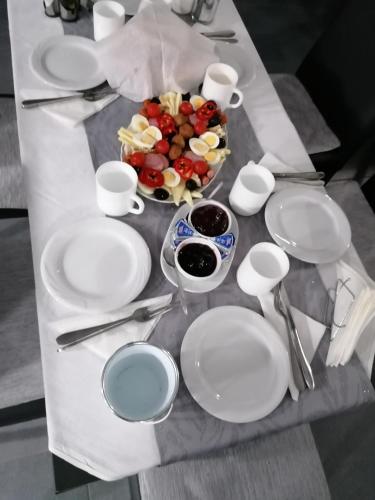 een tafel met witte borden en lepels en een schaal met fruit bij Casa Mara in Ocna Şugatag