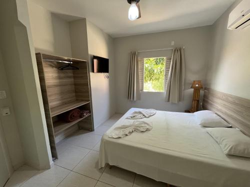 a bedroom with a white bed and a window at Solar do Cerrado Hotel in Bonito