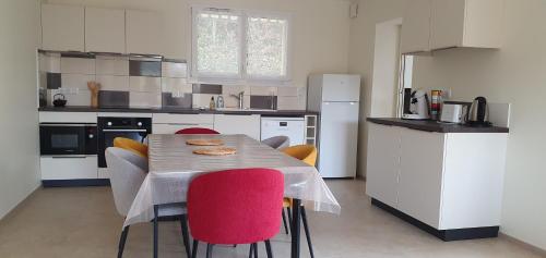 - une cuisine avec une table et des chaises rouges dans l'établissement La Petite Germaine, à Fontaine-sur-Ay