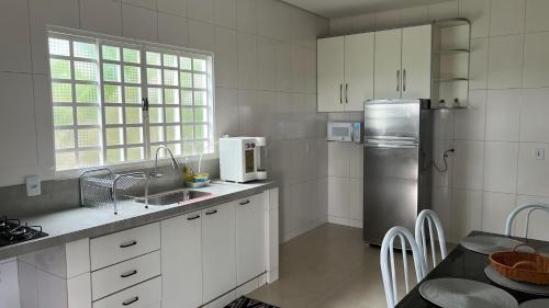 a kitchen with white cabinets and a stainless steel refrigerator at Linda casa em condomínio fechado in Brasilia