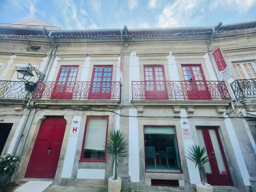 a building with red doors and windows and a palm tree at Rua Grande Hotel in Viana do Castelo