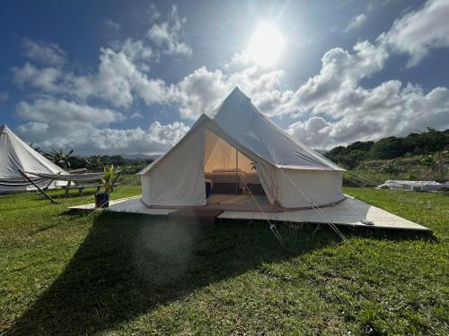 a white tent in a field with the sun at Maleka Farm: Tent Glamping North Shore Oahu in Laie