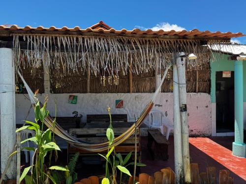 a hammock in front of a building with a bench at Pousada Maré Alta em Boipeba in Ilha de Boipeba