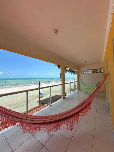 een hangmat op een balkon met uitzicht op het strand bij Pousada das Galés in Maragogi