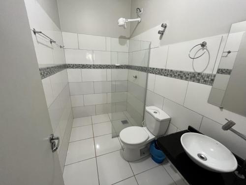 a white bathroom with a toilet and a sink at Solar do Cerrado Hotel in Bonito