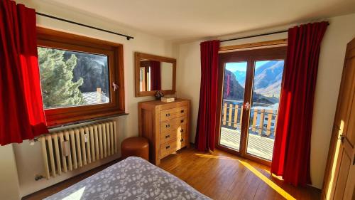 a bedroom with red curtains and a view of a mountain at Chez Ferdinand in Valtournenche