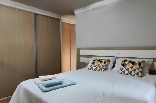 a bedroom with a white bed with two towels on it at Aconchego perto das Cataratas. in Foz do Iguaçu