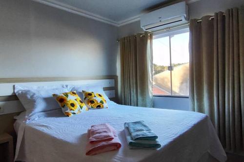 um quarto com uma cama branca e toalhas em Aconchego perto das Cataratas. em Foz do Iguaçu