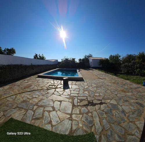 a swimming pool on a stone patio with the sun shining at Ferroa Guest House in Cano