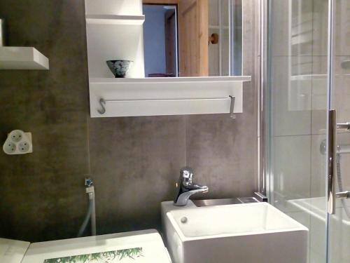 une salle de bain blanche avec un lavabo et un miroir dans l'établissement Studio Rénové au Pied des Pistes avec Balcon et Wifi - FR-1-344-949, aux Menuires