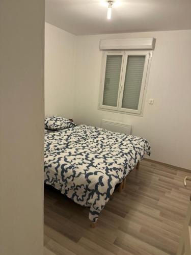 um quarto com uma cama com um edredão preto e branco em Appartement 8 personnes max em Villelongue-de-la-Salanque
