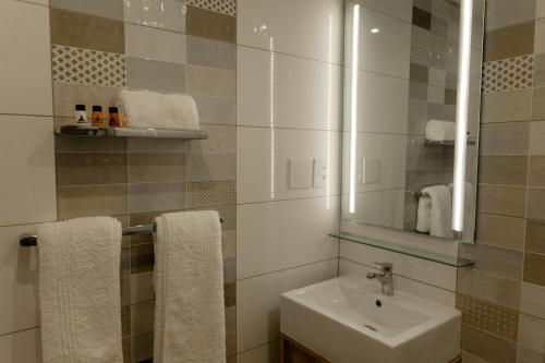 y baño con lavabo, espejo y toallas. en Acres Inn Klerksdorp, en Klerksdorp