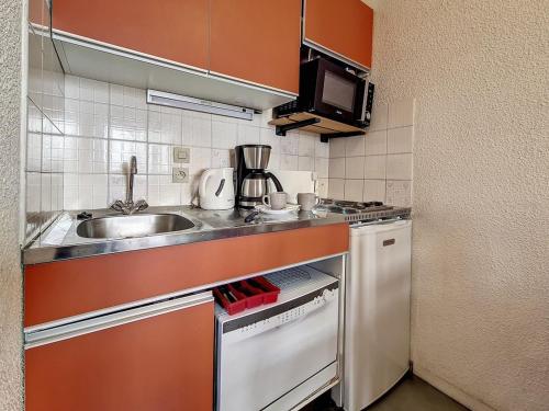 une petite cuisine avec un évier et une cuisinière dans l'établissement Studio classique aux Menuires, balcon, animaux admis - FR-1-344-1038, aux Menuires
