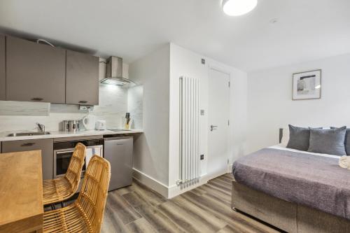 a kitchen and a bedroom with a bed and a table at Sutherland Apartments in London