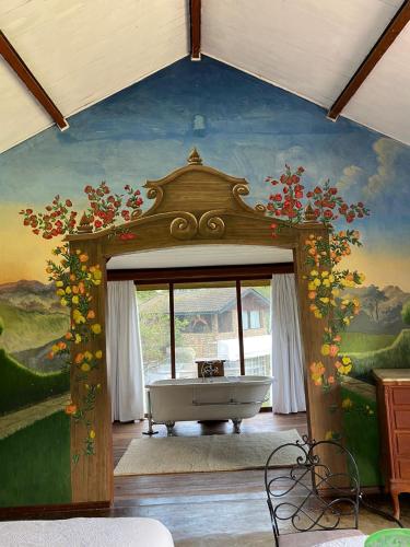 a bathroom with a bath tub in a room with a painting at Chalés do Cachoeirão in Visconde De Maua