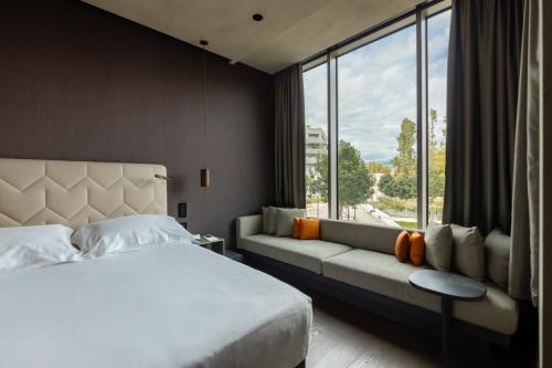 a bedroom with a bed and a couch and a window at Hotel VIU Milan in Milan