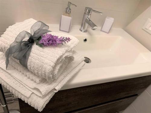 un lavandino in bagno con asciugamano e un fiore sopra di Comfortable Apartment in Sant'Orsola a Bologna