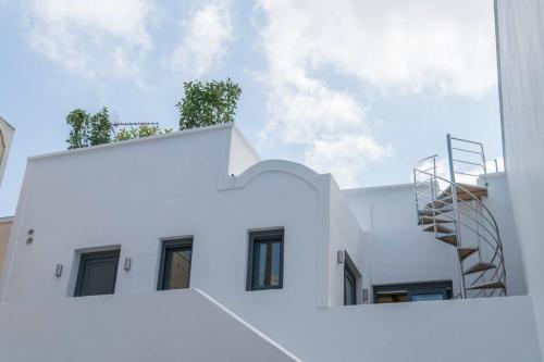 a white building with a staircase on top of it at Nostos Apartments Fira in Fira