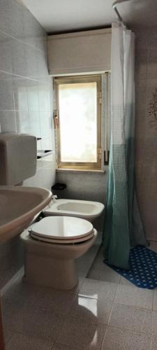 a bathroom with a toilet and a sink and a window at Giusi's House in Cava dʼAliga