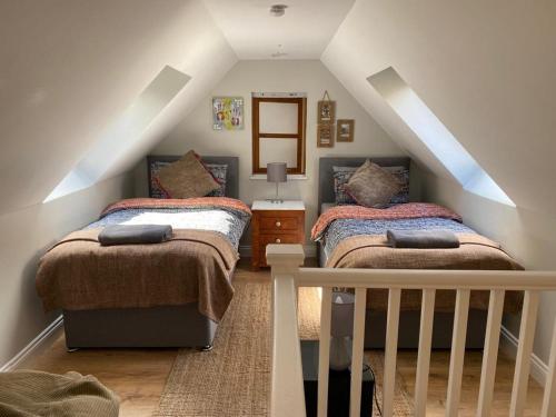 een slaapkamer op zolder met 2 bedden en een trap bij Eakie House Apartments - Kinlochleven in Kinlochleven
