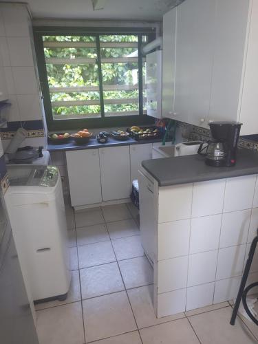 a kitchen with white cabinets and a window in it at B&B Santo Domingo Chile ENGLISH SPOKEN Gran Departamento compartido frente al mar PARQUE TRICAO bird sanctuary 14kms 9miles away DESAYUNO ESTACIONAMIENTO Y WIFI GRATIS Free parking wifi and breakfast in Santo Domingo