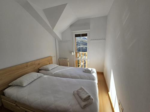 2 camas en una habitación blanca con ventana en IMEDA Apartamentos BUENAVISTA LODGE en Sierra Nevada