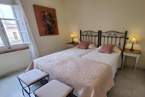 a bedroom with two beds and two chairs and a window at Magdalena Plaza City Center 2 in Seville