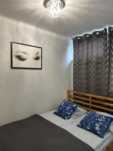 a bedroom with a bed with blue pillows and a chandelier at Coser Apartamenty III in Warsaw