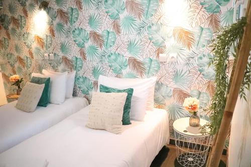 サン・ガシアン・デ・ボワにあるMaria Grazia Hotelのベッド2台、枕、壁紙が備わる客室です。