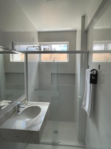 a white bathroom with a sink and a shower at Regente Hotel in Pato Branco