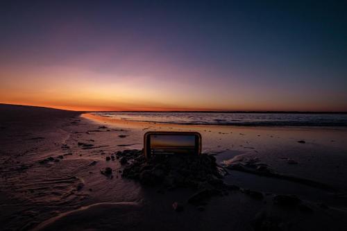 a chair sitting on the beach at sunset at Sea Vista Motel in Topsail Beach