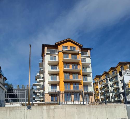 卡爾帕奇的住宿－Apartamenty z widokiem na Śnieżkę，围栏前高高的公寓楼