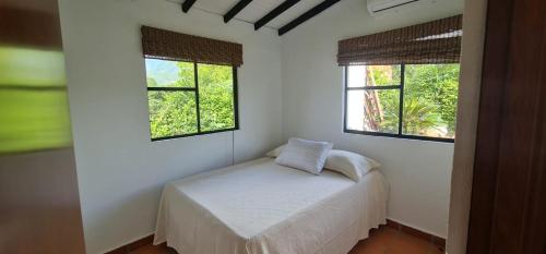 um pequeno quarto com uma cama e duas janelas em EL PARAISO em Sopetrán