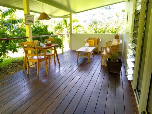 eine Veranda mit einem Tisch und Stühlen auf einer Terrasse in der Unterkunft TAHAA - Fare Motoi in Tiva