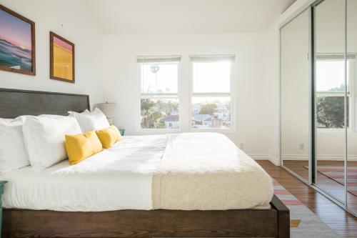 1 dormitorio blanco con 1 cama grande con almohadas amarillas en Sonrisa II by AvantStay Home w Views in Pacific Beach Mins to Belmont Park, en San Diego