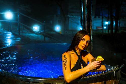 una mujer sentada en una piscina con una bebida en Basztogród, en Sanok
