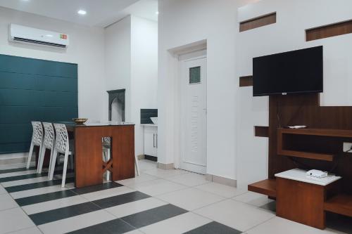 a living room with a tv and a table and chairs at Royad Calicut Farm House - Premium Villa with Pool Inside a Farm in Kozhikode