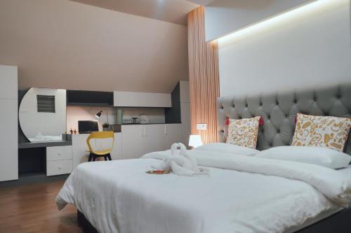 a bedroom with two white beds and a kitchen at Royad Calicut Farm House - Premium Villa with Pool Inside a Farm in Kozhikode