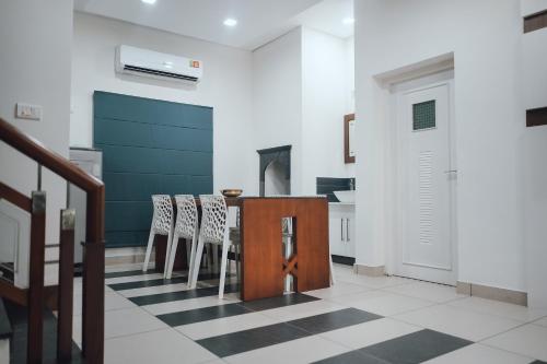 a kitchen with a table and chairs on a checkered floor at Royad Calicut Farm House - Premium Villa with Pool Inside a Farm in Kozhikode