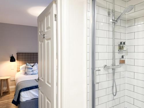 a bathroom with a shower and a bed and a shower at Beach House Hotel in Seahouses