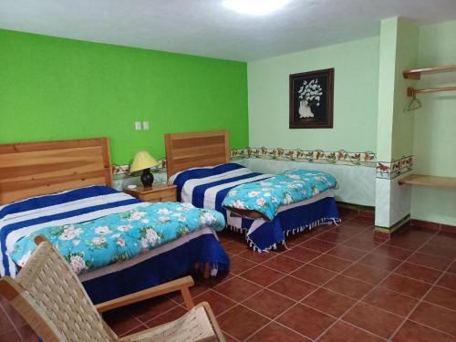 two beds in a room with green walls at Plaza Don Gabino Hotel y Restaurante in Mineral de Angangueo