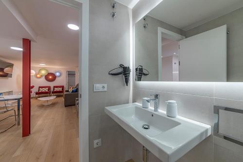 baño blanco con lavabo y sala de estar. en AlohaMundi Martínez Montañés en Sevilla