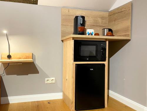a kitchen with a microwave and a black refrigerator at Suite zwischen den Wehlen in Westerdeichstrich