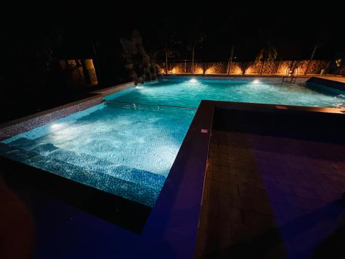 a large swimming pool at night with lights at Farm Fort Resort By Luxdens Hotels in Kozhikode