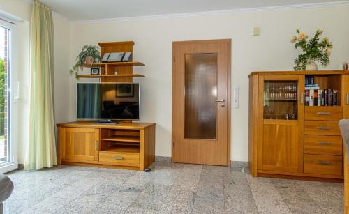 een woonkamer met een houten entertainmentcentrum en een deur bij Ferienwohnung Ruteplate in Esens