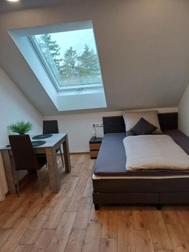 Schlafzimmer mit einem Bett, einem Tisch und einem Dachfenster in der Unterkunft Bianca's Ferienwohnungen in Giebelstadt