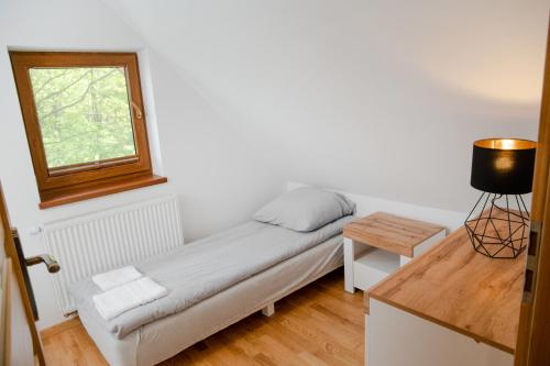 a small bed in a room with a window at Domki Łowisko Wieniec in Gdów