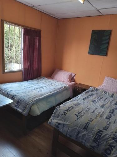 1 dormitorio con 2 camas y ventana en Hostal Armando, en Valparaíso